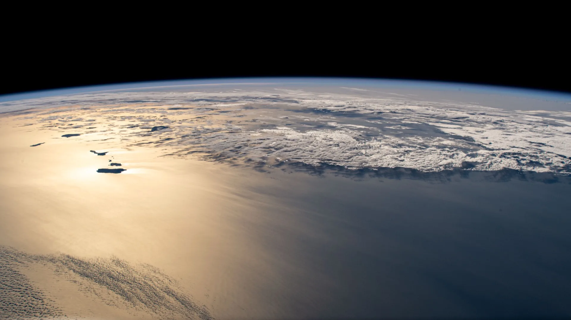 Earth limb from the ISS, atmosphere glowing against the dark